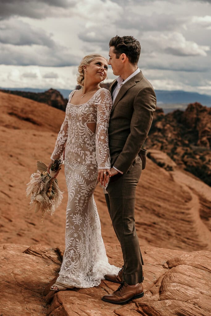 Bride and groom hold hands and look at each other during their elopement.