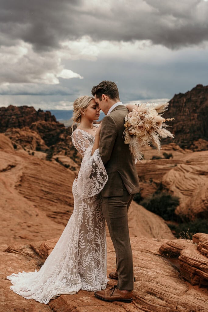 Bride and groom stand forehead to forehead in the desert during their elopement.