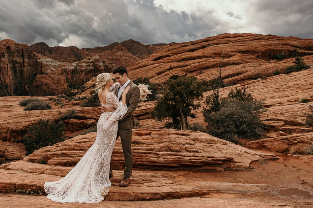 A couple in wedding attire stand on the petrified sand dunes in Utah during their elopement.