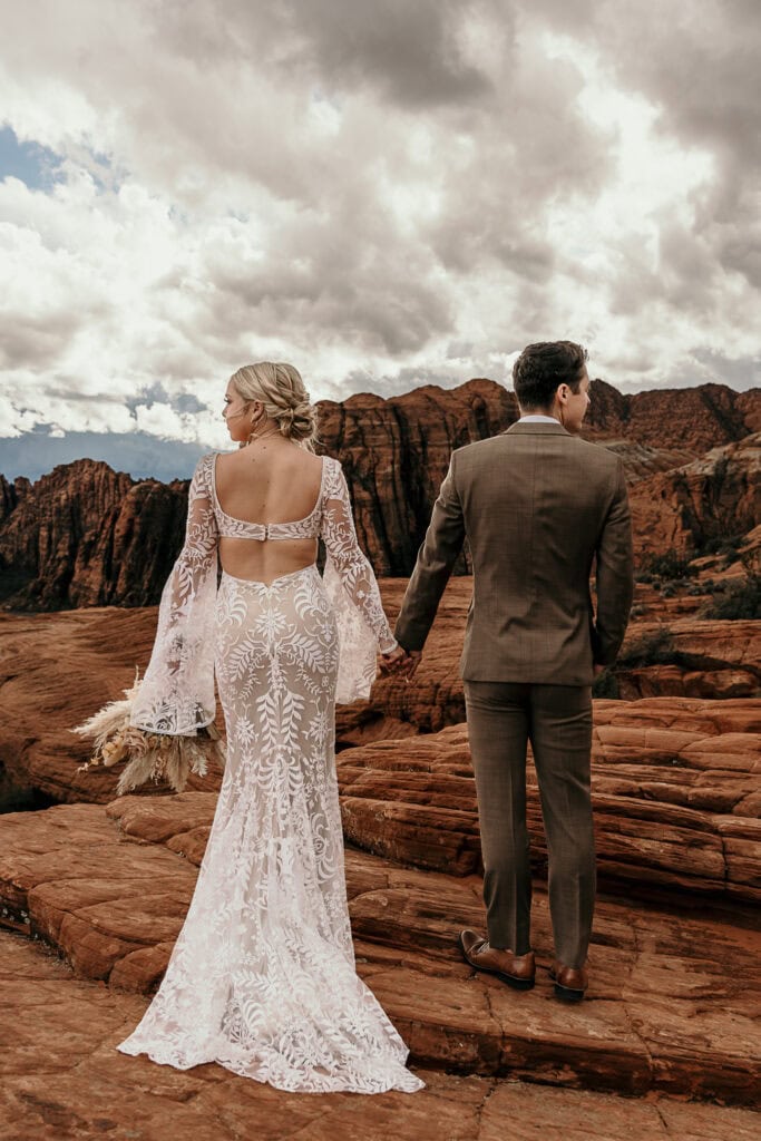 Jayson and Skyler look out across the petrified sand dunes in St. George. They're in wedding attire.