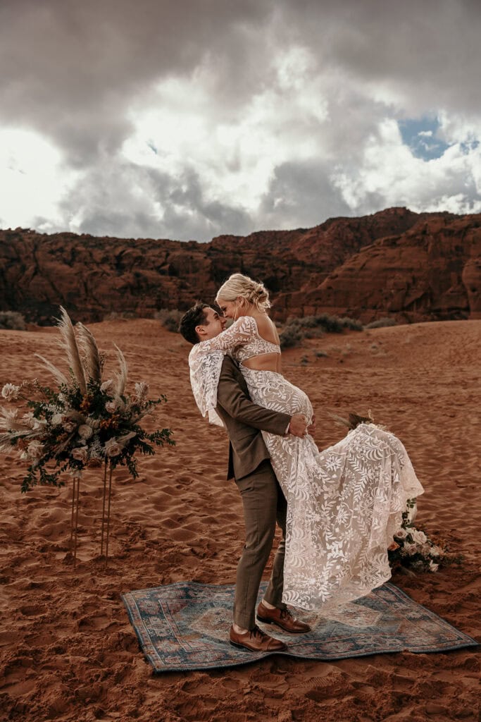 Bride and groom kiss passionately during their ceremony in the desert.