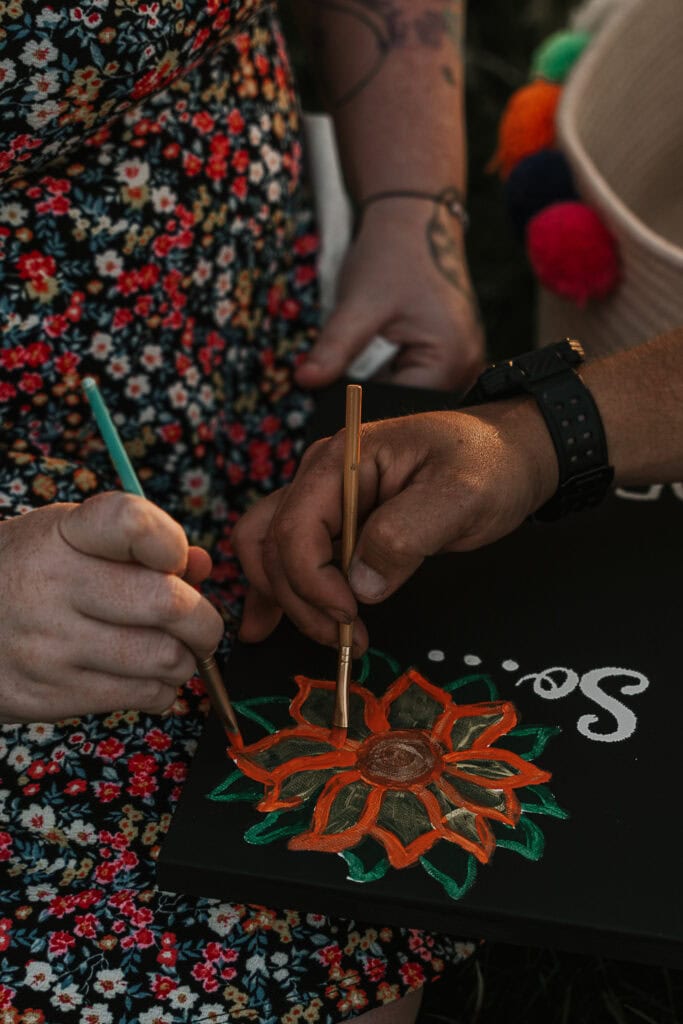 A couple paints a flower together.