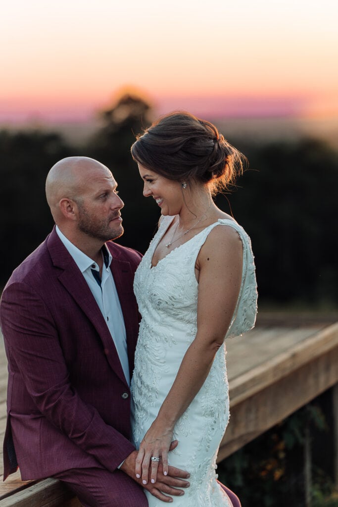 Bride and groom smile at each other during a beautiful sunset.