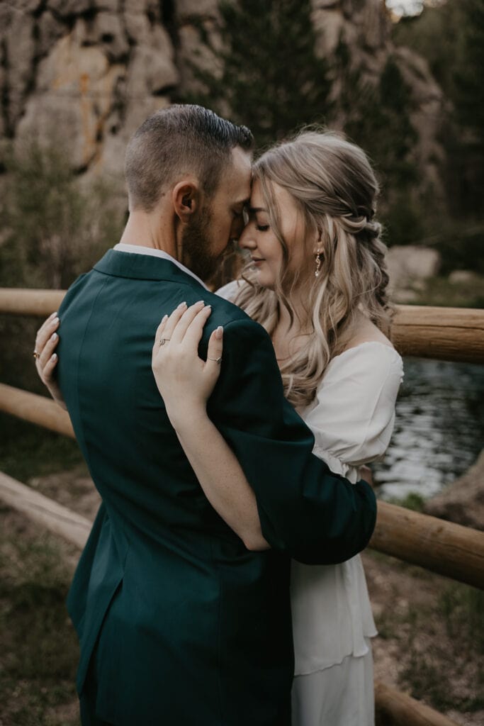 Eloped couple stands forehead to forehead celebrating Colorado elopement ceremony near a river in Rocky Mountains