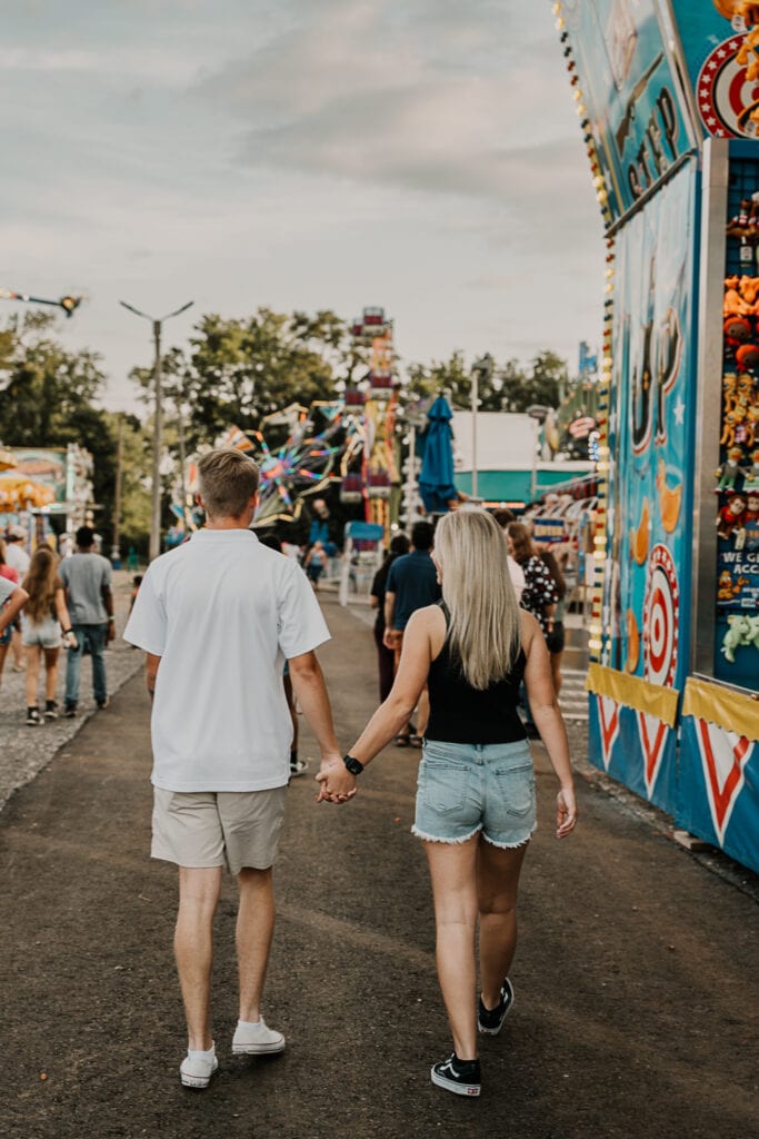 Couple walks with their arms around each other at the county fair.