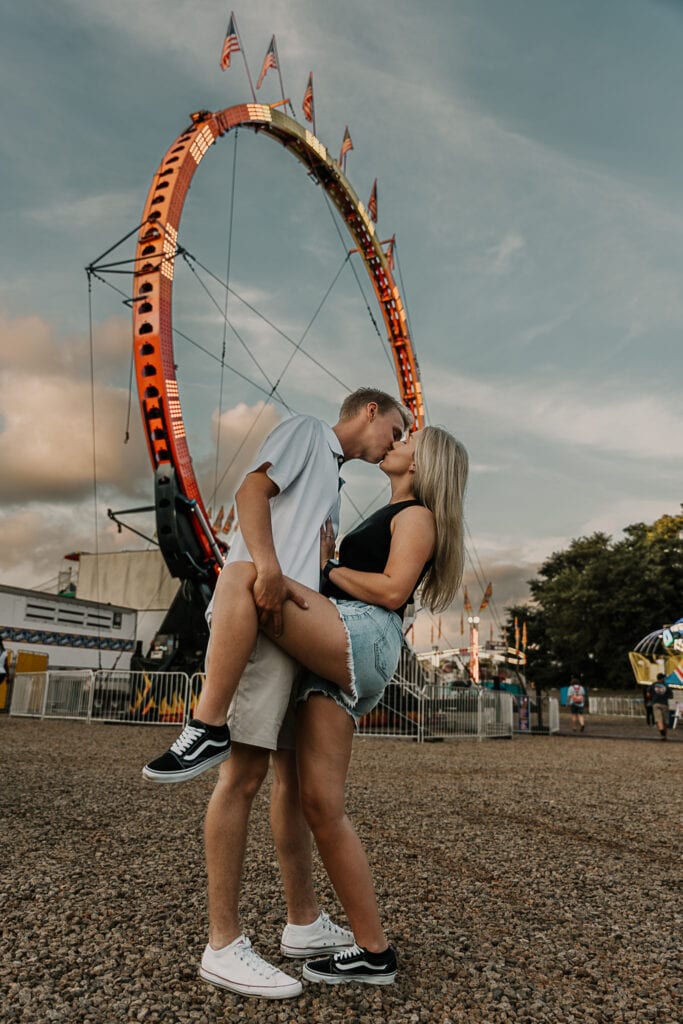 Man dip kisses his fiancé in front of a wheel at the Montgomery County Fair.