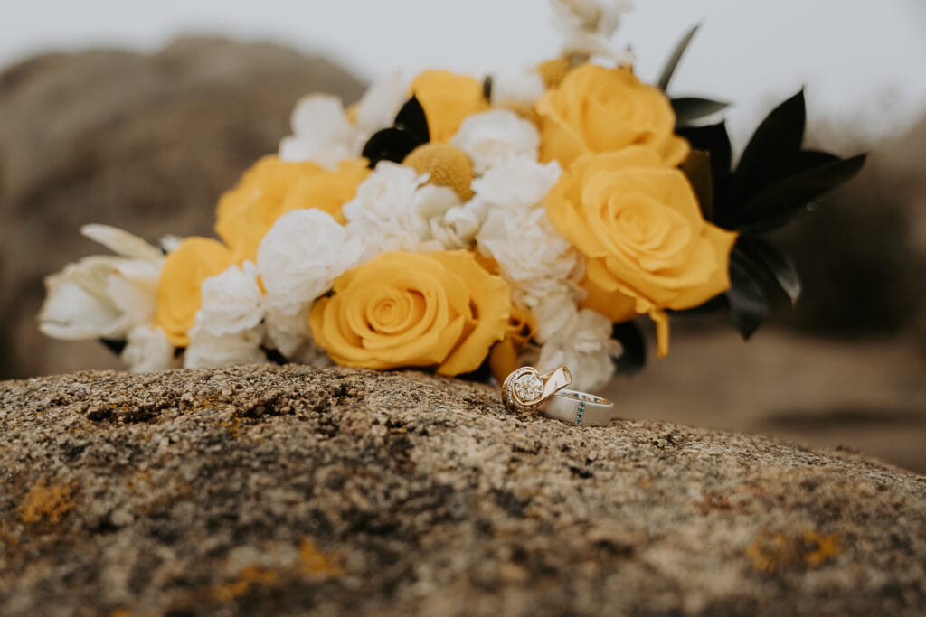 A yellow wedding bouquet on top of rocks in the Rocky Mountains. The foggy forest is in the background.