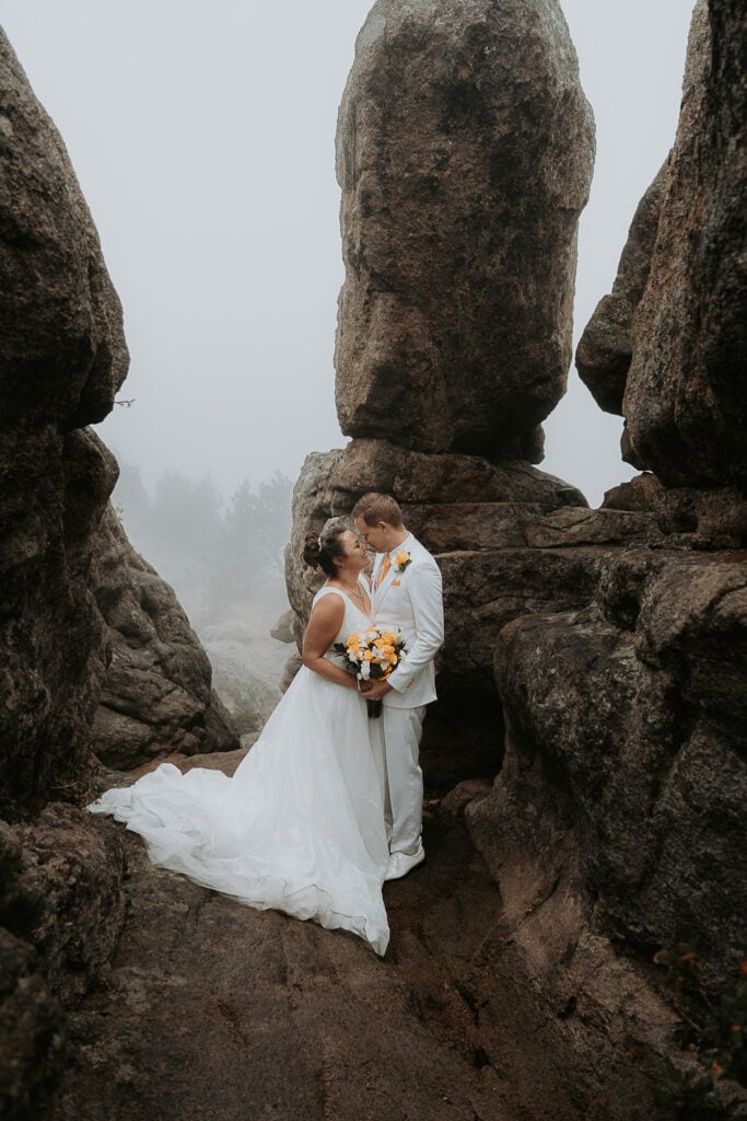 Couple leans against a rock on Kruger Rock Trail to kiss during hiking elopement in Estes Park, Colorado.