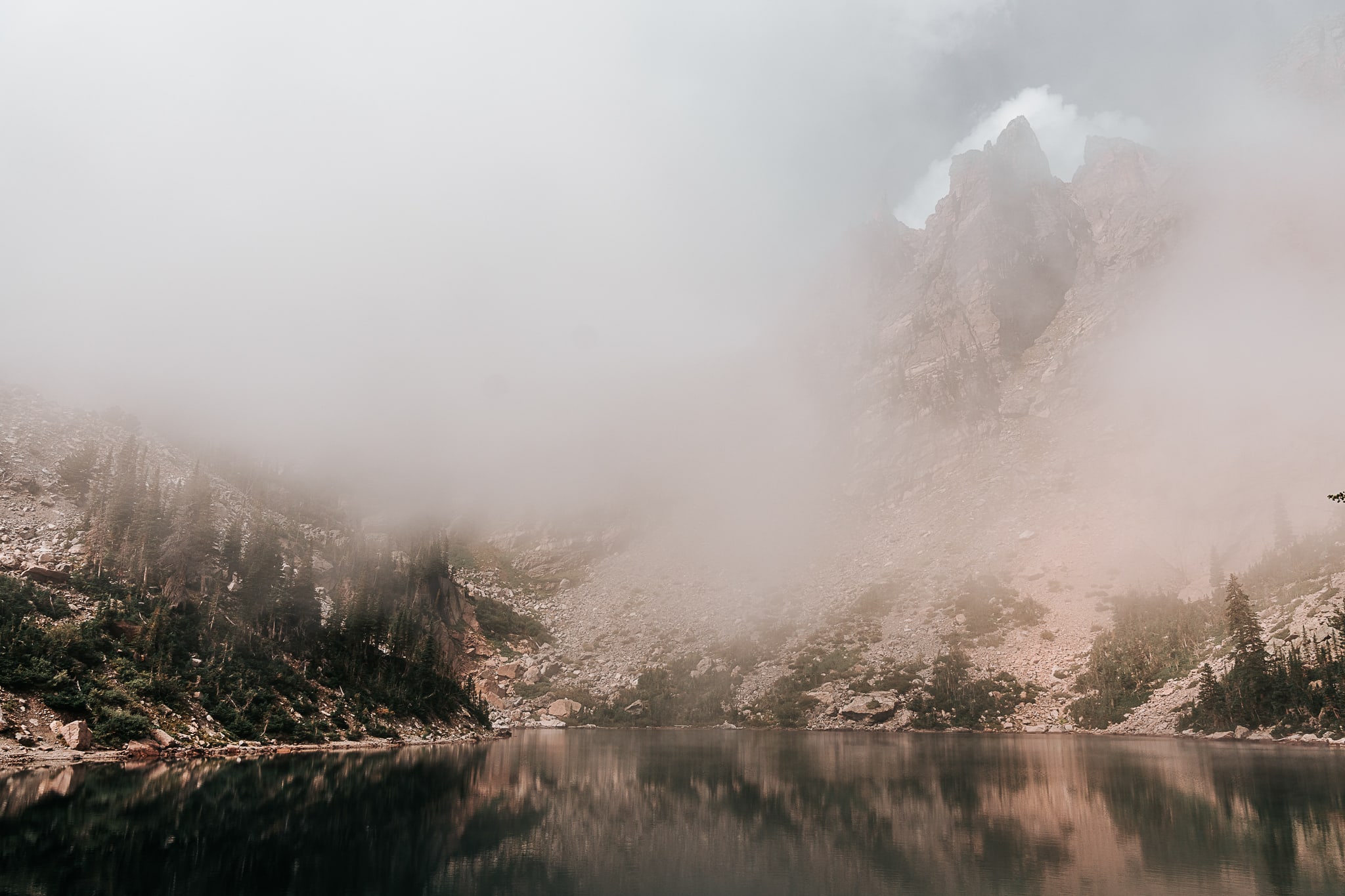 Fog is lifting at Dream Lake and you can see the Rocky Mountains starting to peak through the clouds.