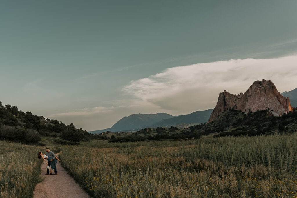 Man kisses woman in a dip with Colorado mountains in the background. She is holding a bouquet at her side.