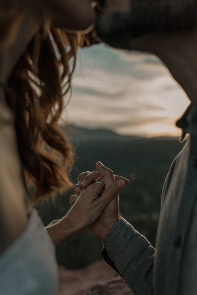 Couple kisses and holds hands in the middle of the natural window of the Siamese twins in Garden of the Gods, CO