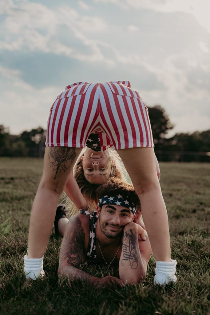 Alex lays on the ground between Michelle's feet as she peeks through her legs at the camera.