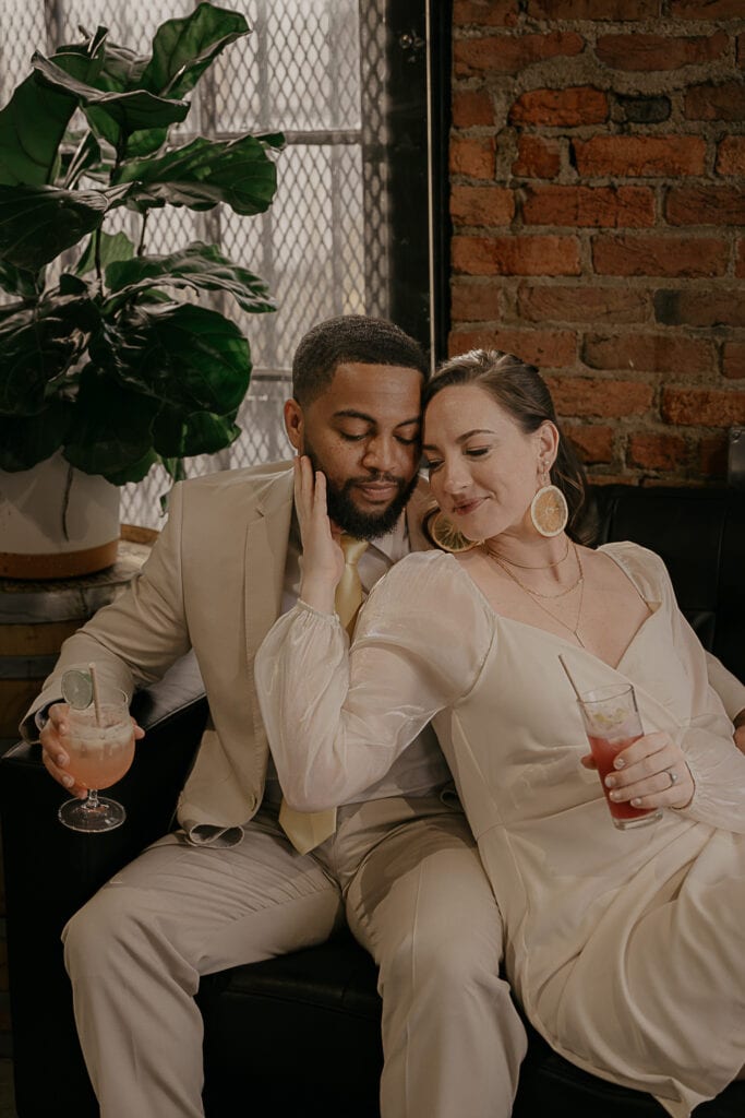 Dakota & Kristin snuggle on leather couch in Corsair Distillery during their all day elopement.