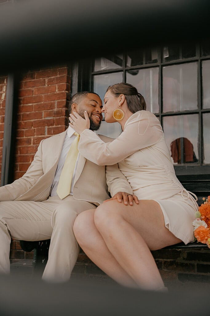 Couple sits on a bench outside Corsair Distillery during urban Nashville elopement.