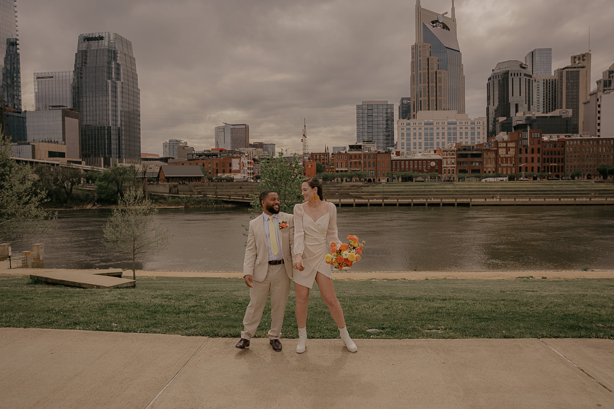 Couple stands side by side on the sidewalk in Cumberland Park, Nashville Tennessee
