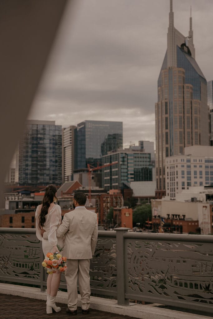 Just eloped couple looks out at downtown Nashville from Pedestrian bridge above the Cumberland River