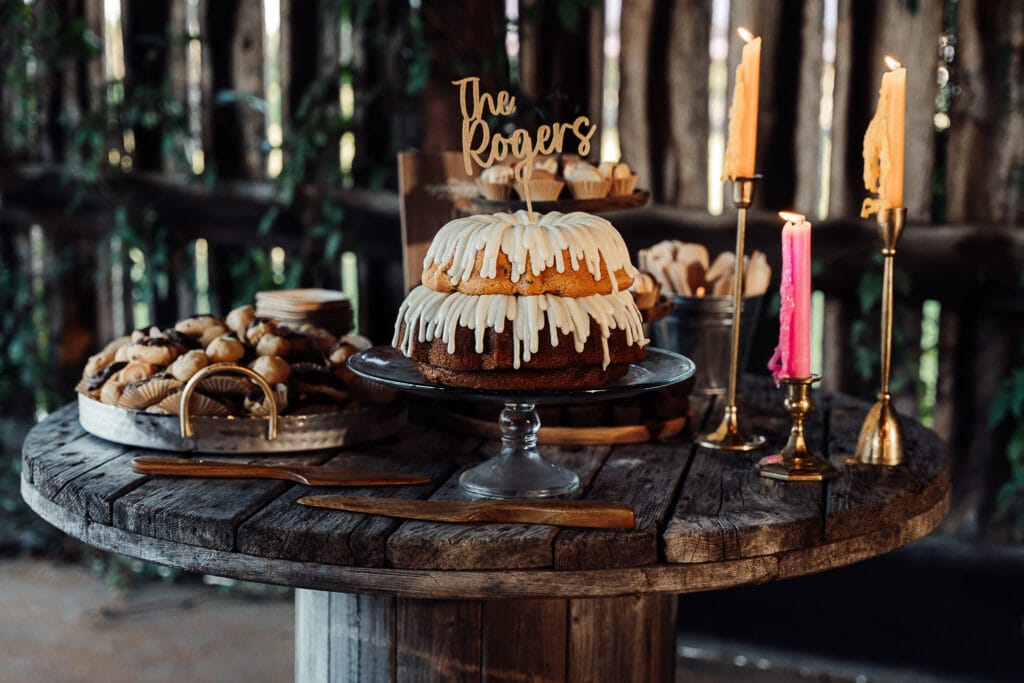 A decorated bundt cake surrounded by candles on a wooden table at a reception.