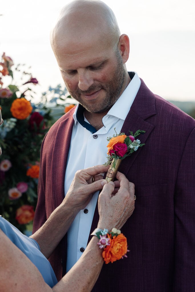 Groom's mom pins on his vividly colored boutonniere.
