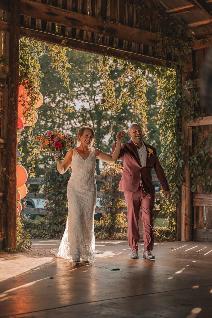 Bride & Groom walk into a barn for their wedding reception.