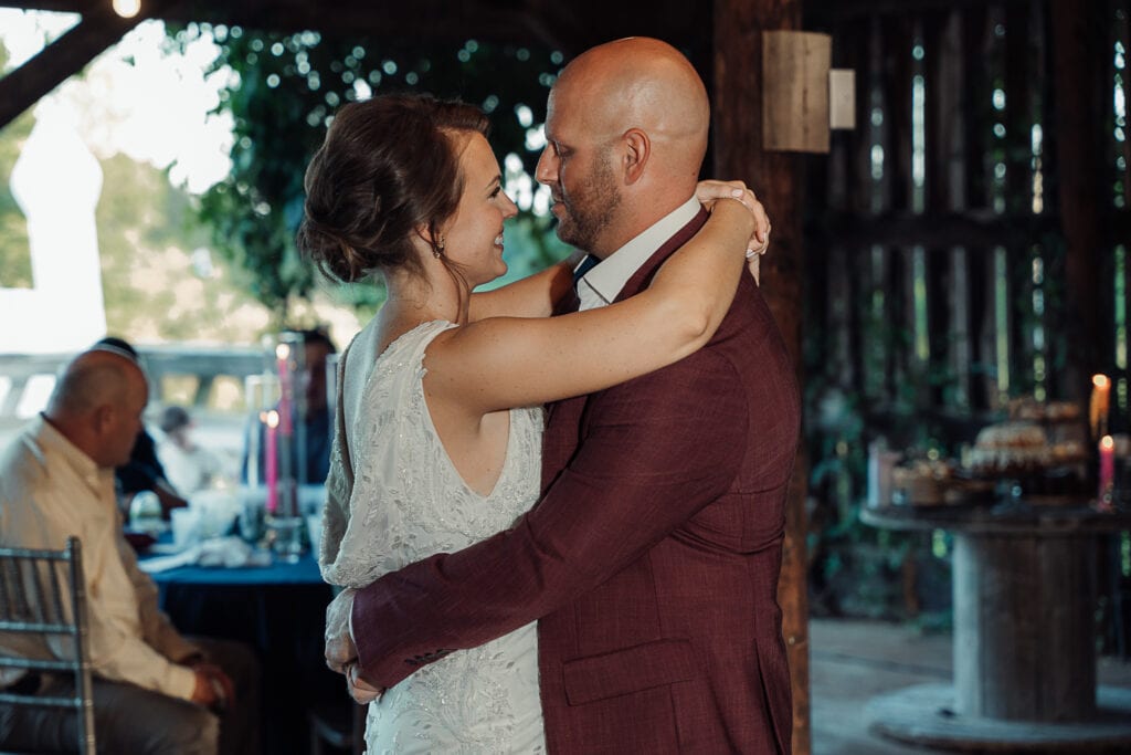 A man and woman have their first dance at their reception in a rustic barn.