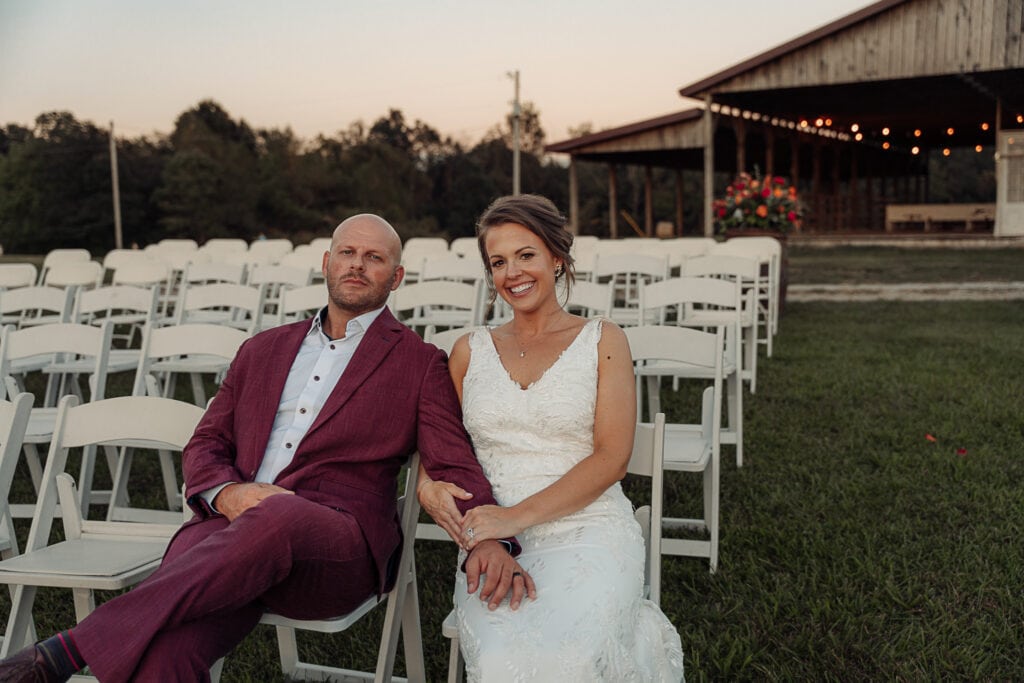 Bride & Groom sit in the empty seats of their outdoor venue after their wedding.