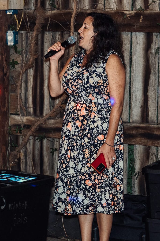 A guest sings at a wedding reception in a barn.