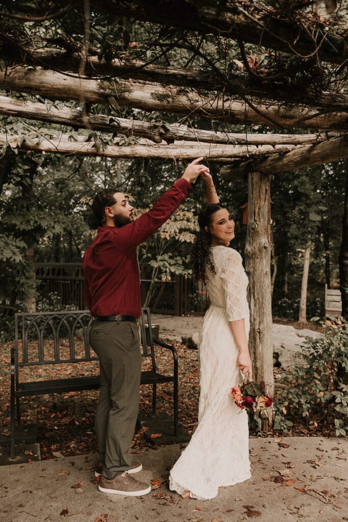 Groom spins Bride around under a garden arch during their first look on their wedding day.