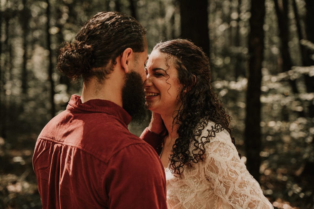 Mady and Ezekiel laugh together with their noses touching. Her nose is crinkled up, and his hand is on the side of her face.