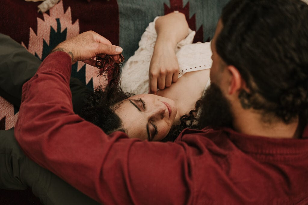 Bride is laying with her head in the groom's lap as he looks down at her during a private picnic at their elopement.