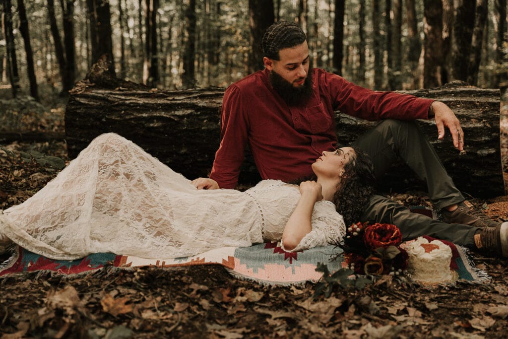 Bride and Groom have a picnic with wedding cake during their elopement in the forest. 