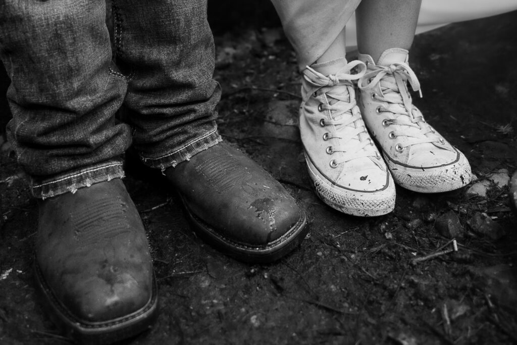 Black and white photo of bride and groom's wet and muddy shoes during rainy waterfall elopement.