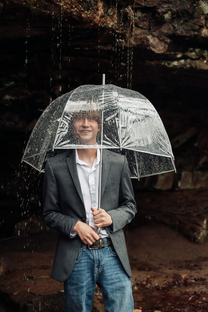 Candid moment of the groom being silly with an umbrella over his face.