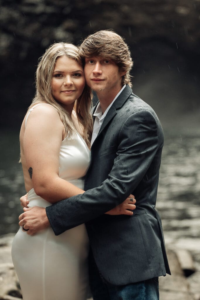 Closeup of Ashlyn & Brent embracing and standing cheek to cheek in front of waterfall pool.