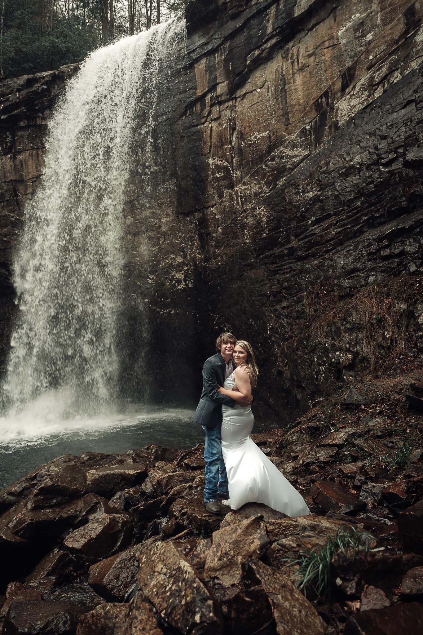 Bride and Groom embrace in a kiss with waterfall to the side of them.