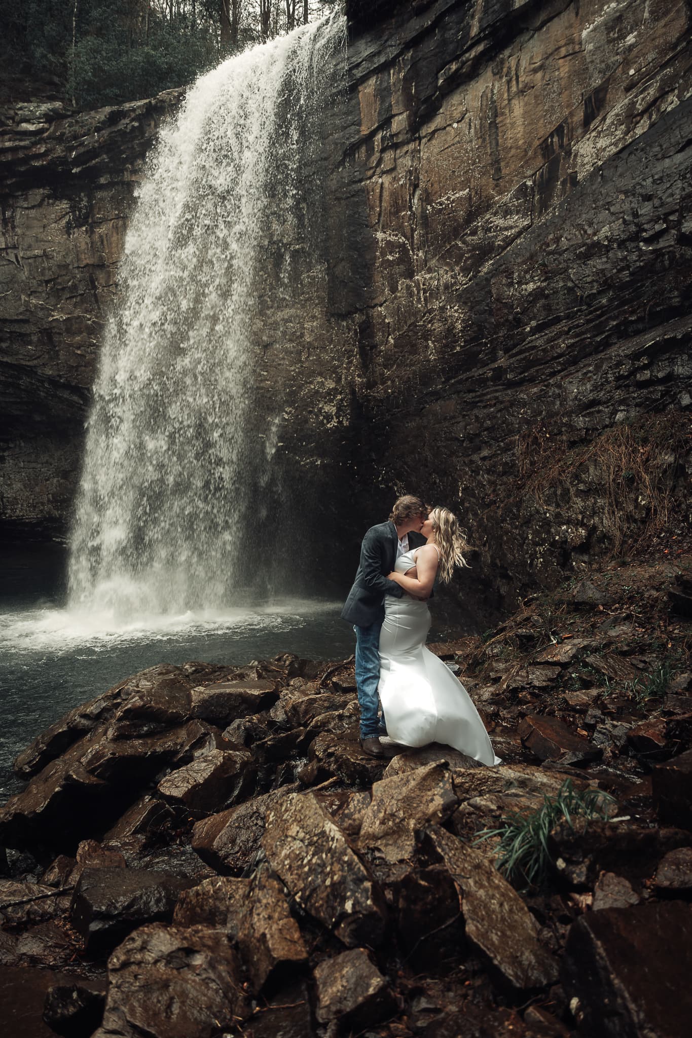 Ashlyn & Brent share a passionate kiss at the base of Foster Falls. The wind is blowing their hair and her dress.