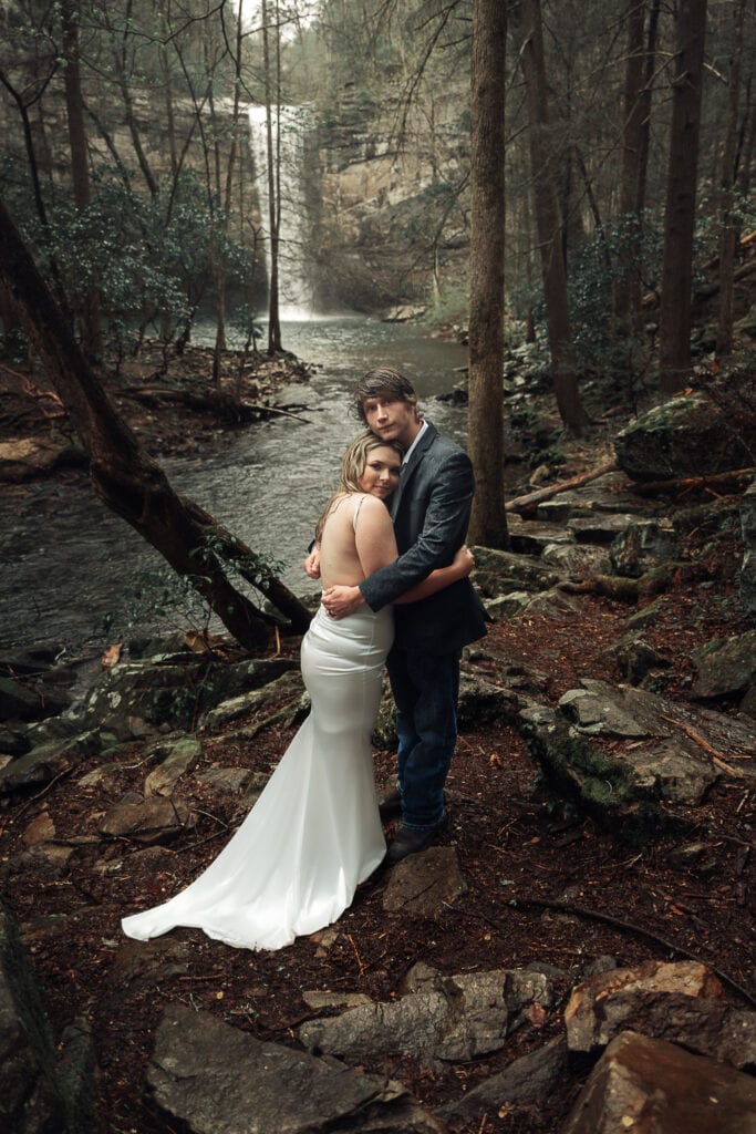 Ashlyn leans her head on Brent's shoulder with her arm around him while they stand on swinging bridge in Tennessee