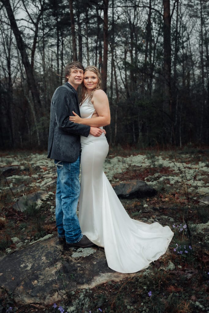 Soaked Bride & Groom pose on each side of Foster Falls Fiery Gizzard trail sign after their rainy elopement.