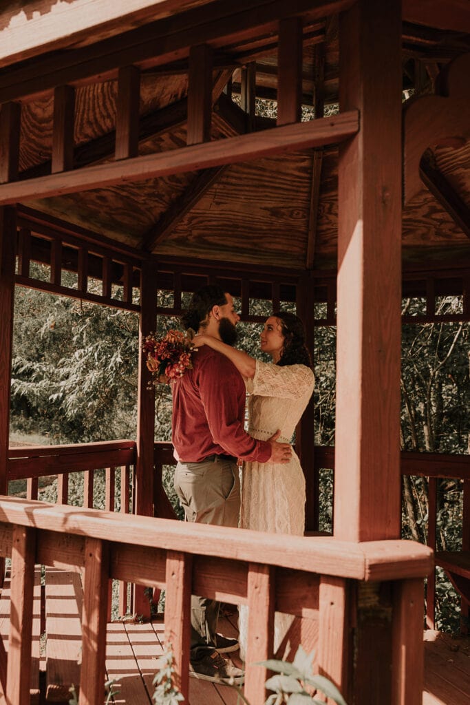 A couple shares an embrace in a gazebo, during a private moment on their elopement day.