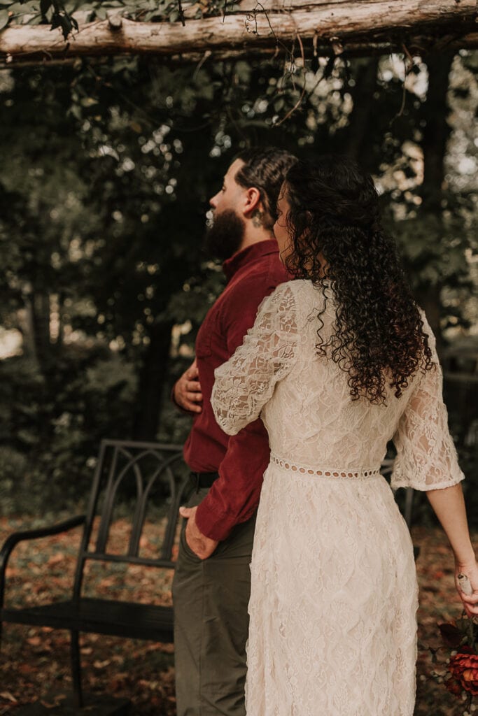 A woman puts her hand on a man's arm before he turns around to look at her for their wedding day first look.