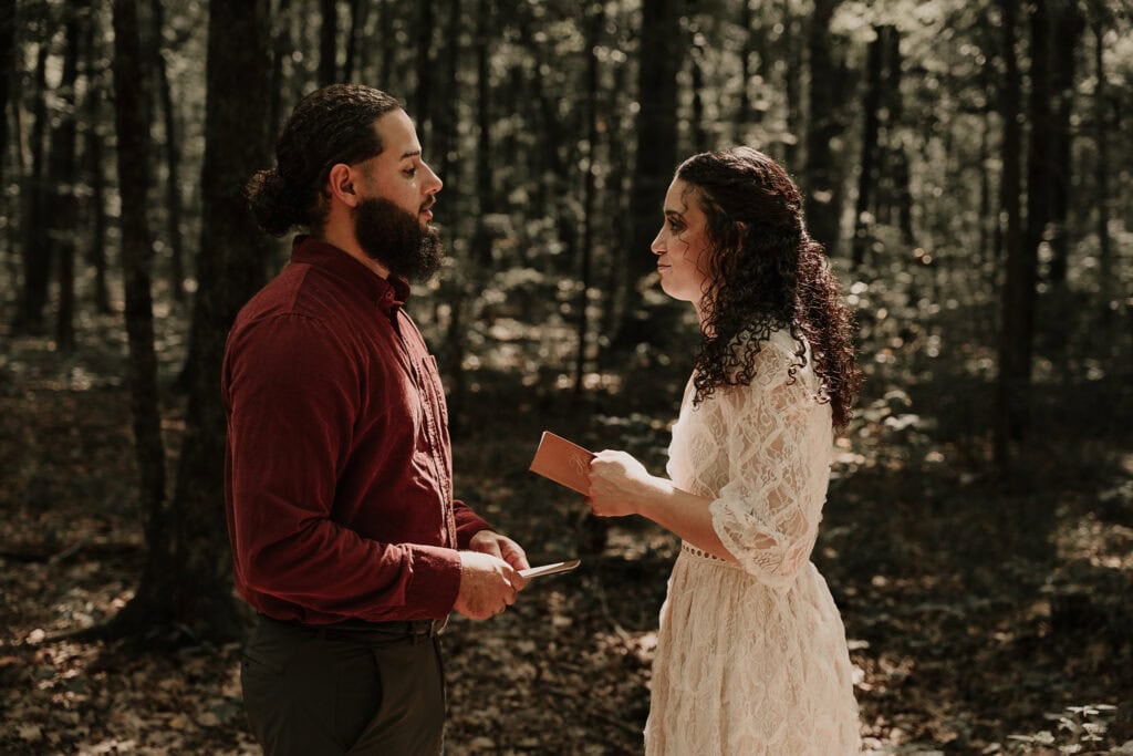 Mady & Ezekiel say their vows in the forest as the sunlight shines down on them.