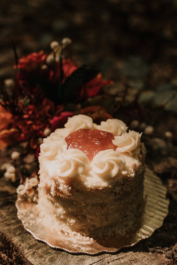 A small carmel apple wedding cake with the bridal bouquet in the background.