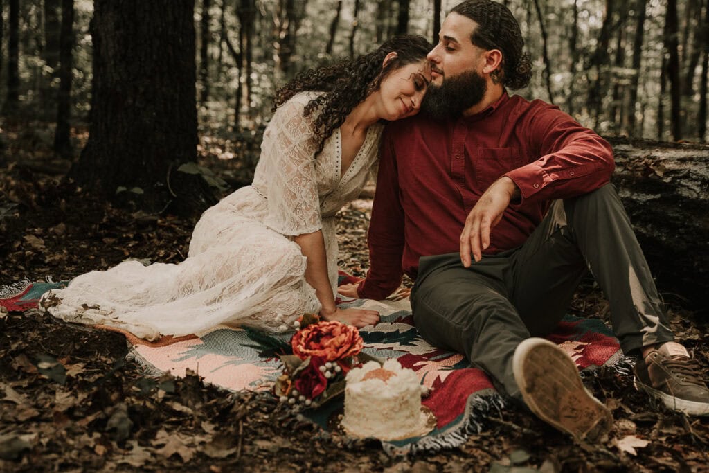 Mady rests her head on Ezekiel's shoulder during their elopement picnic.