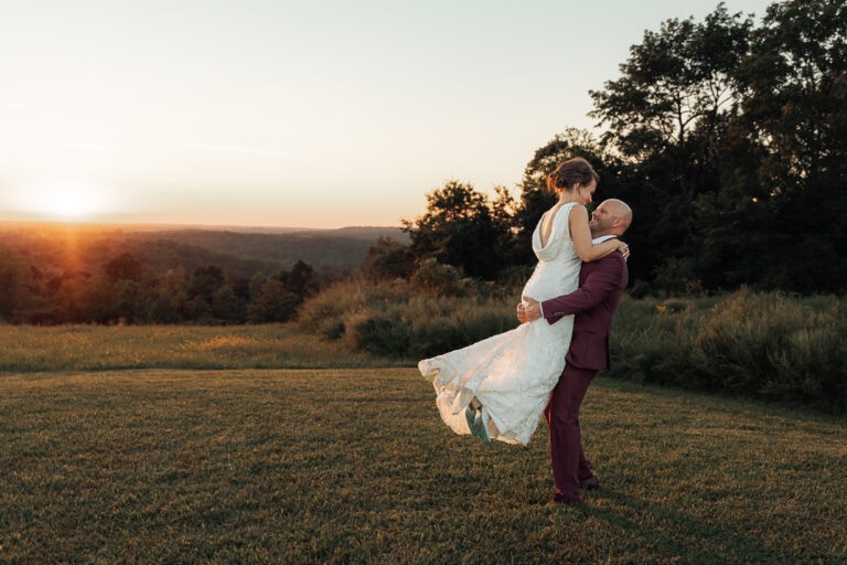 AJ swings Lauren around in his arms in front of the sunset as they laugh during their elopement.