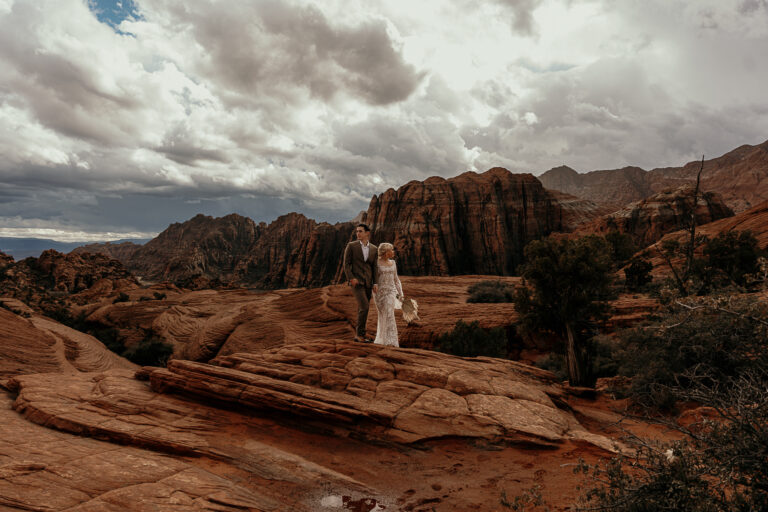 Groom and Bride look in opposite directions while holding hands after wedding ceremony on top of rocks in St George Utah