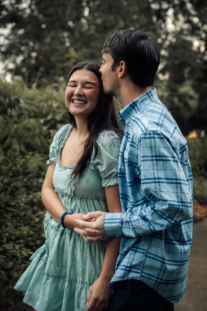 Couple laughs as they play in the rain during photoshoot.