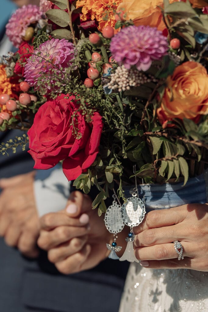 A closeup of a bride carrying her bouquet with keepsakes attached to it in honor of her grandparents.