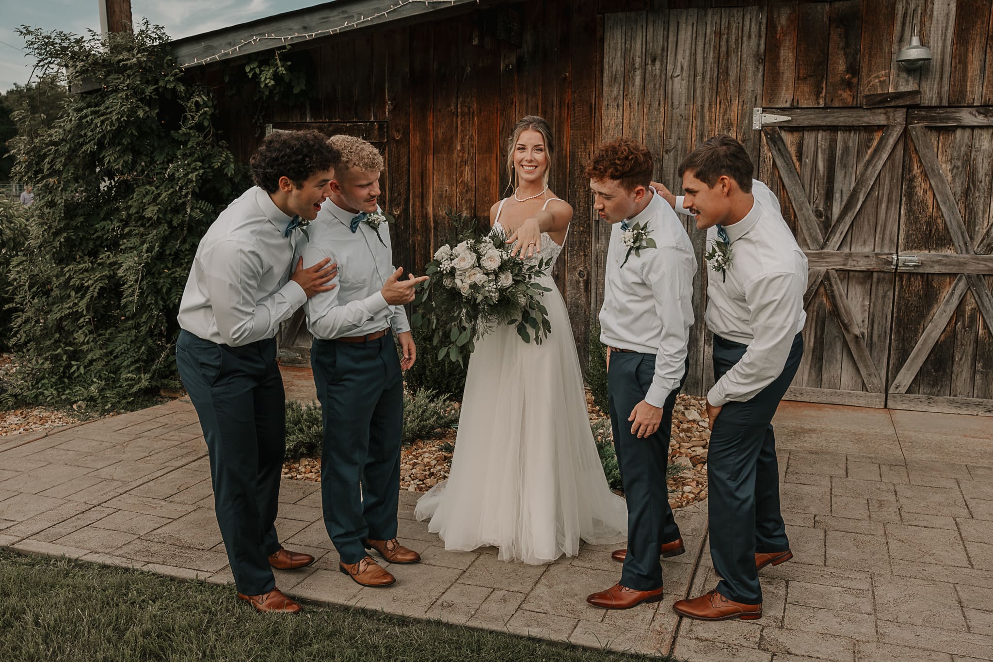 Bride shows her wedding ring off to the groomsmen