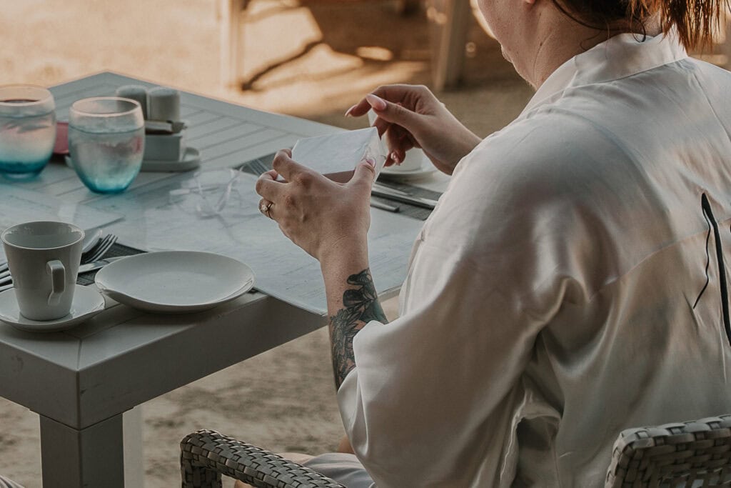 A bride opens up a gift from the groom at the breakfast table.