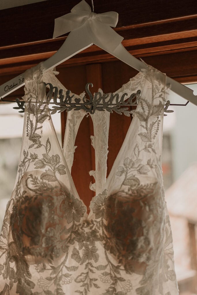 A customized hanger for a wedding dress has Mrs. Spencer in sparkly wooden letters.