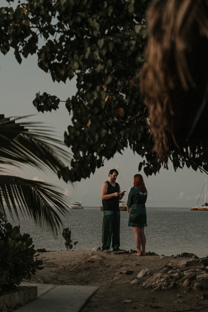 A man and woman, in matching silk pjs, exchange private vows on the beach.